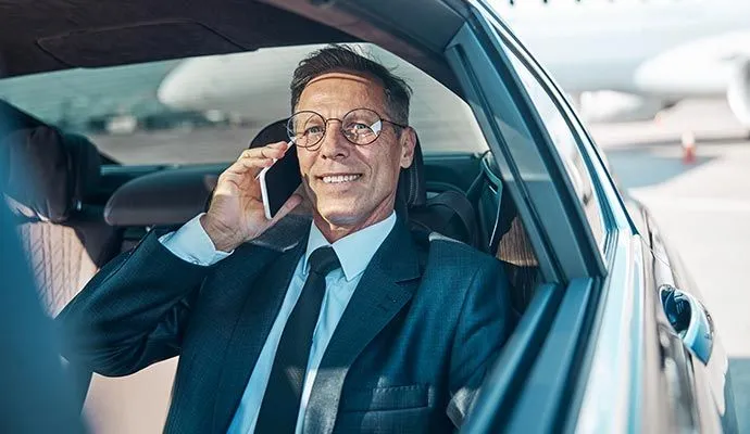 Businessman talking on the phone in the back seat of a luxury car