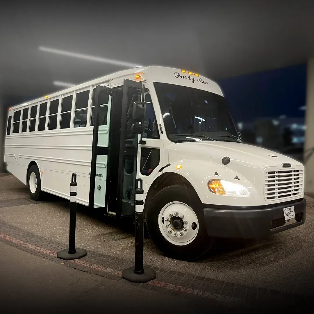 White party bus parked at night with its lights glowing