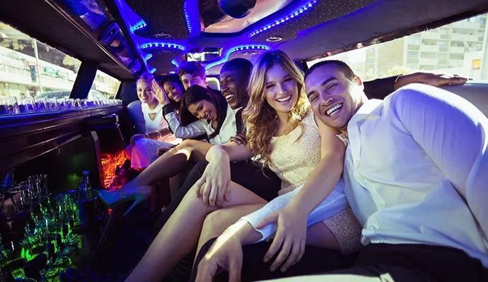 Bachelorette party guests celebrating inside a limousine lit with purple and neon lights