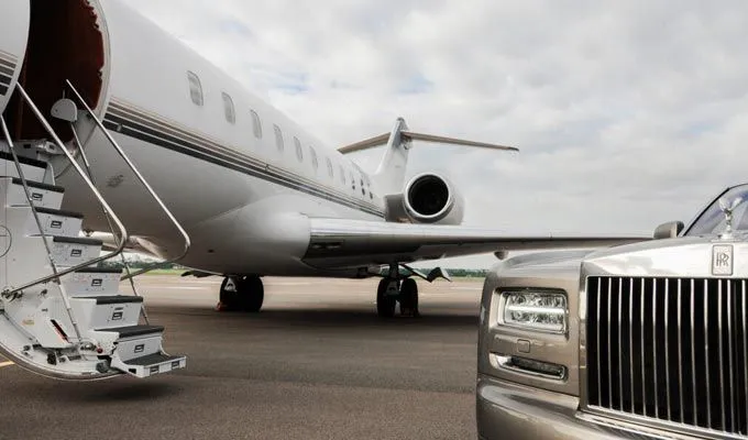 Rolls-Royce parked in front of a private jet