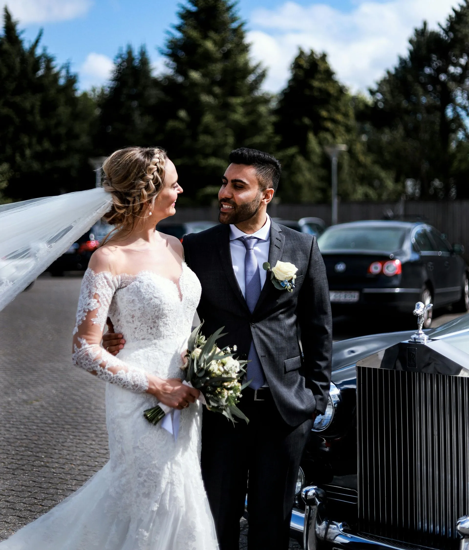 Newlywed couple beside a black limousine